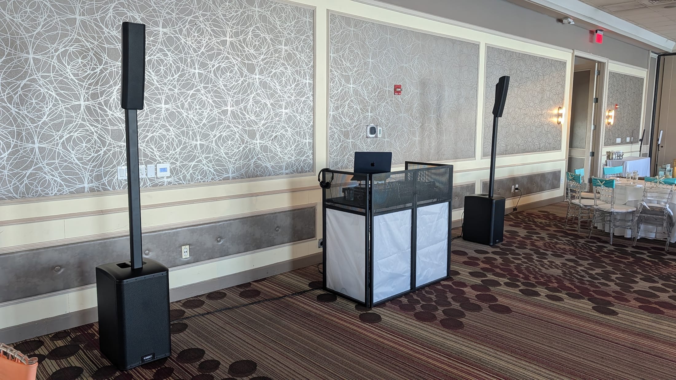 Clean DJ booth and QSC column speaker setup in a Miami ballroom